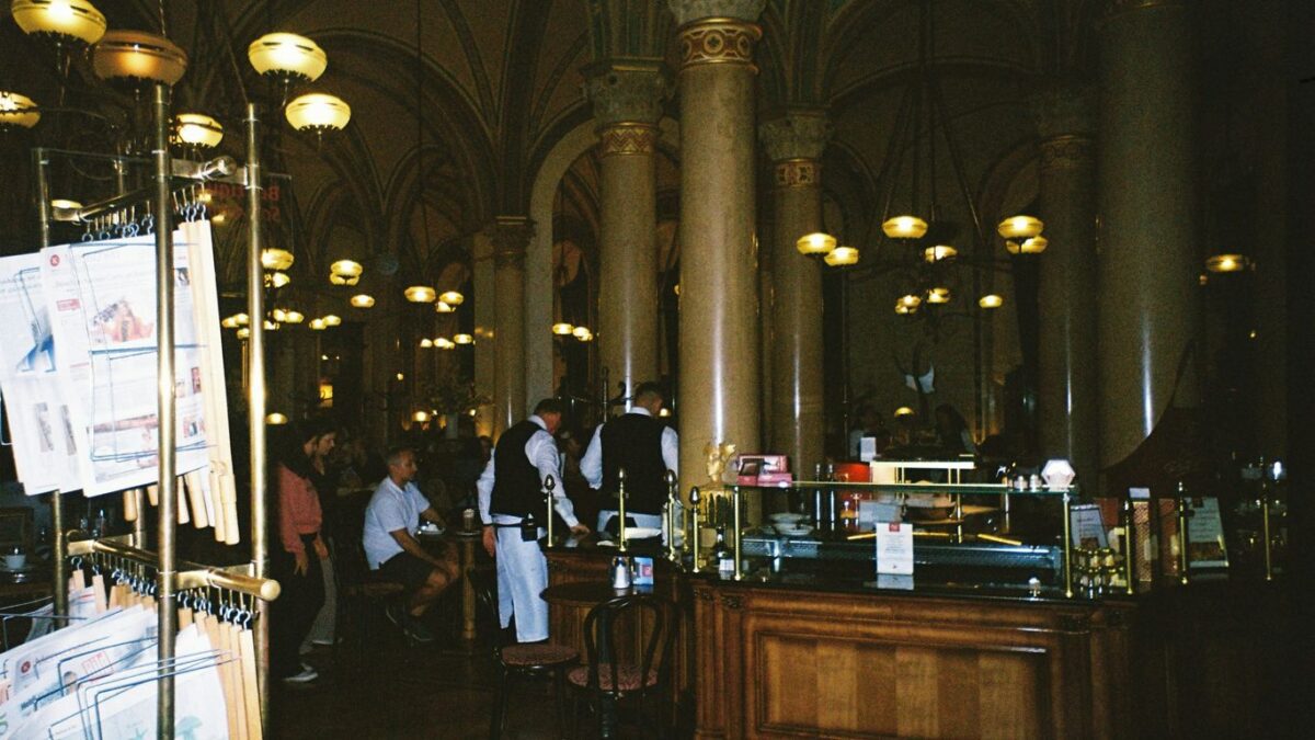 People in a dimly lit ornate cafe with columns