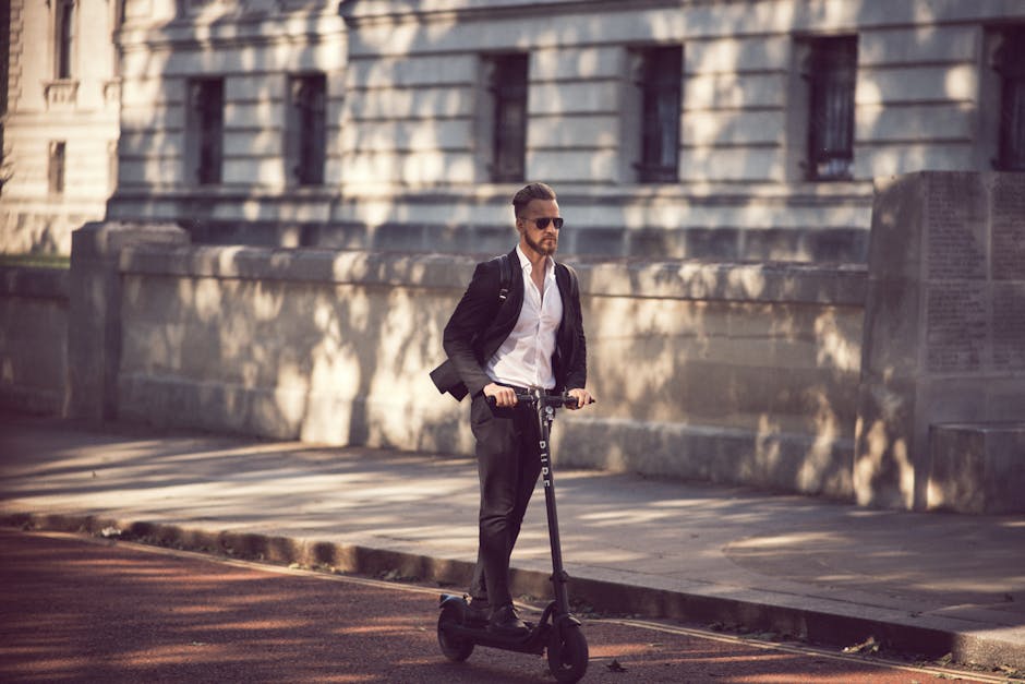 Man in a suit riding an electric scooter on a city street, showcasing modern urban transportation.