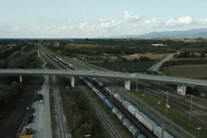 Freight train with containers traveling under a bridge in Offenburg, Germany.