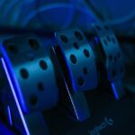 Detailed shot of gaming pedals illuminated by blue light, perfect for racing simulation setups.