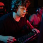 A dedicated gamer immersed in a gaming session with colorful lighting and headphones.