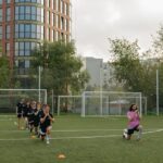 A group of kids performing warm-up exercises with their coach on a soccer field.