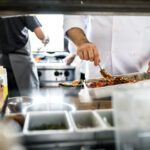 och regeneriert ein Gericht im GN-Behälter in der Profiküche – veranschaulicht den Cook-&-Chill-Prozess von Produktion bis Service.