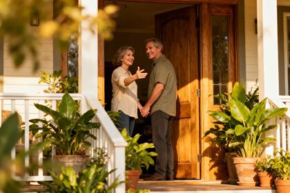 Paar steht glücklich vor seinem Haus