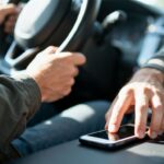 Fahrerin greift nach Smartphone während der Fahrt