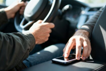 Fahrerin greift nach Smartphone während der Fahrt