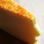 A piece of cheese sitting on top of a wooden table