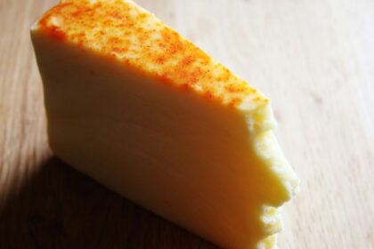 A piece of cheese sitting on top of a wooden table