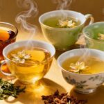 Verschiedene Teesorten in Tassen und lose Teeblätter.