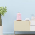 A modern kitchen interior featuring a pastel color scheme with decorative kitchenware and plant.