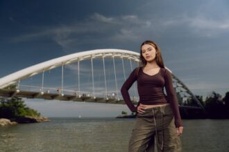 Stylish female model posing by Humber Bay Arch Bridge in Toronto, outdoors on a sunny day.