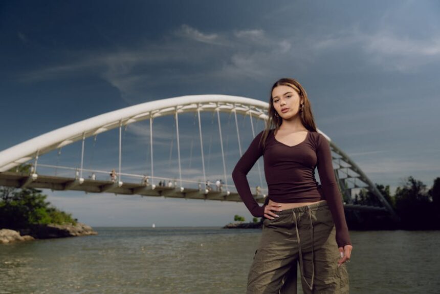 Stylish female model posing by Humber Bay Arch Bridge in Toronto, outdoors on a sunny day.