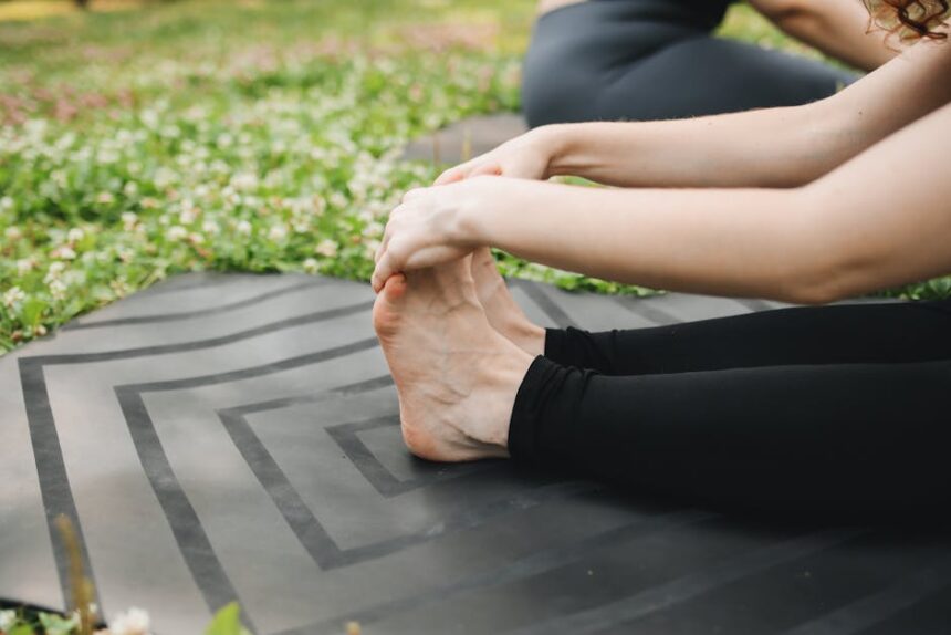Close-up of a woman stretching on a yoga mat outdoors, promoting fitness and wellness.