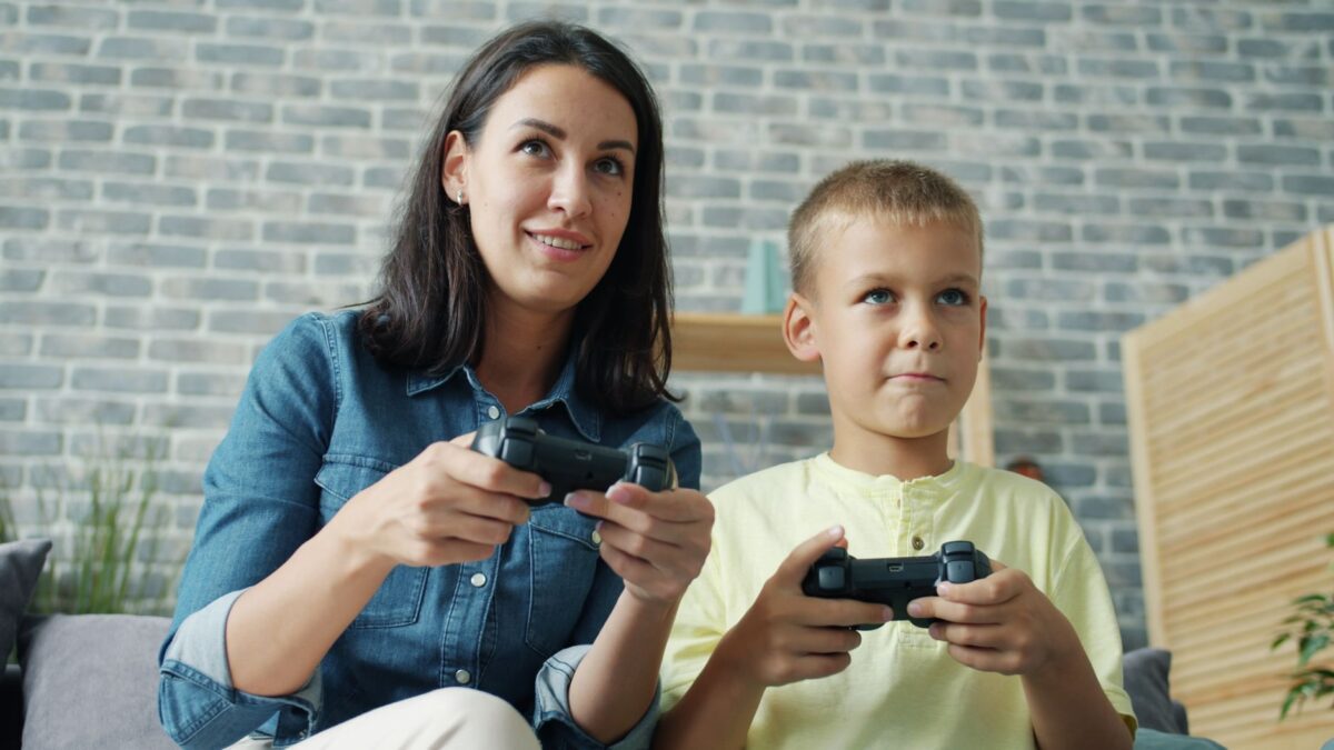 Mother and son enjoy gaming together indoors, creating a joyful bond.