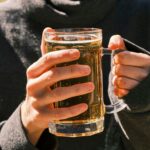 a woman holding a glass of beer in her hands